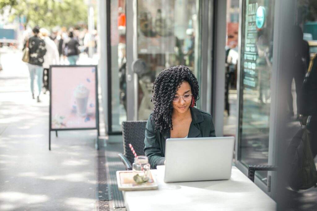 Mulher escrevendo no computador em um café
